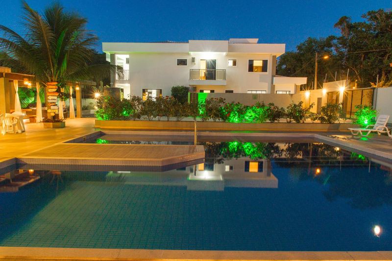 Piscina iluminada à noite com as casas acesas ao fundo