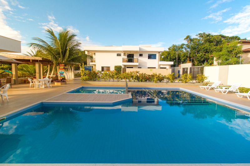 Piscina com espreguiçadeiras e as casas ao fundo