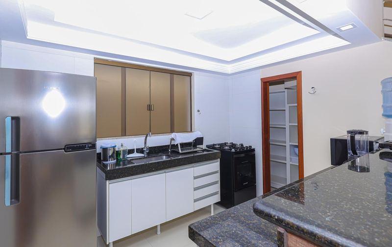 Cozinha com geladeira inox, fogão e bancada de granito