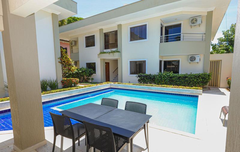 Mesa à beira da piscina com as casas ao fundo