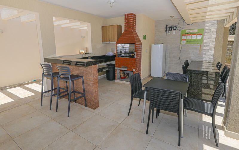 Espaço gourmet coberto com churrasqueira de tijolo, bancada e mesas