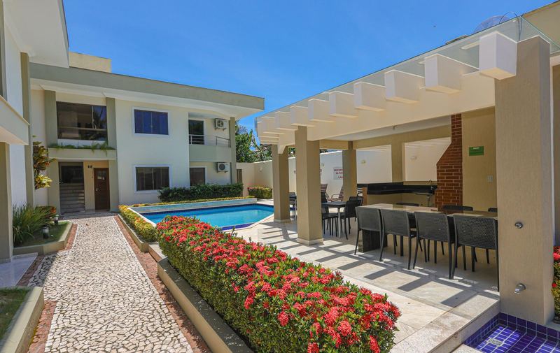 Caminho de pedra entre o jardim florido, a piscina e o espaço gourmet