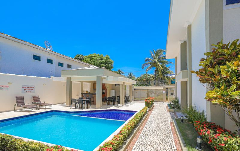 Piscina com espreguiçadeiras e o espaço gourmet ao fundo