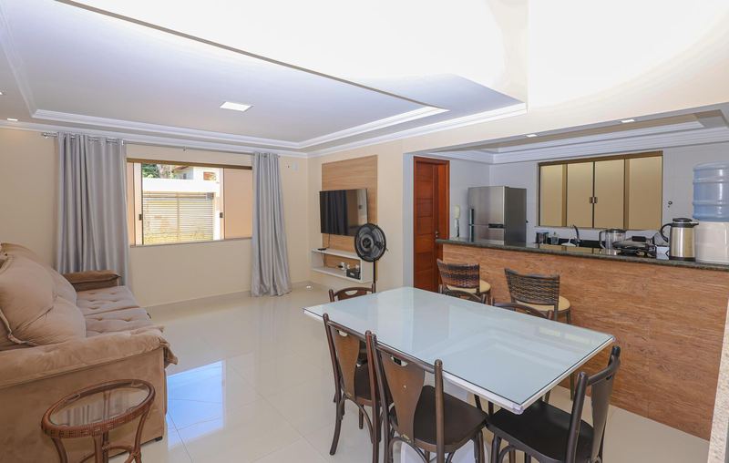 Sala com sofá, mesa de jantar e cozinha ao fundo